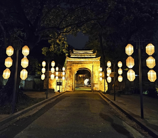 Illuminated entrance with hanging lanterns at night.