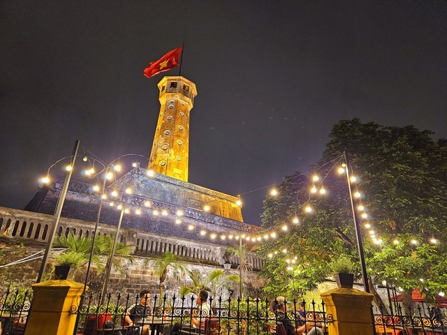 Flag atop an ancient fortress with string lights.