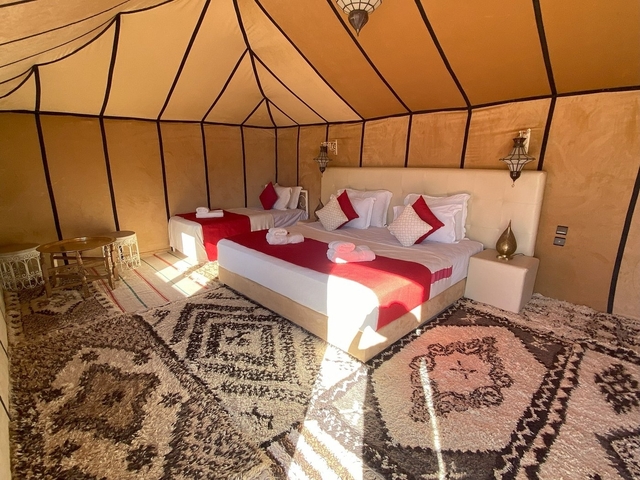 Luxurious tent interior with beds and traditional decor.