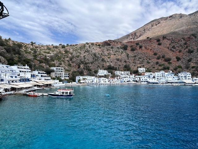 White buildings by the sea with a mountainous background.