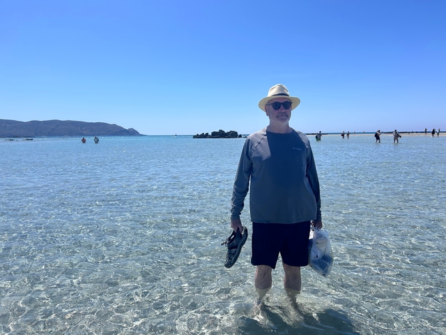 Person standing in clear shallow water on a sunny day.
