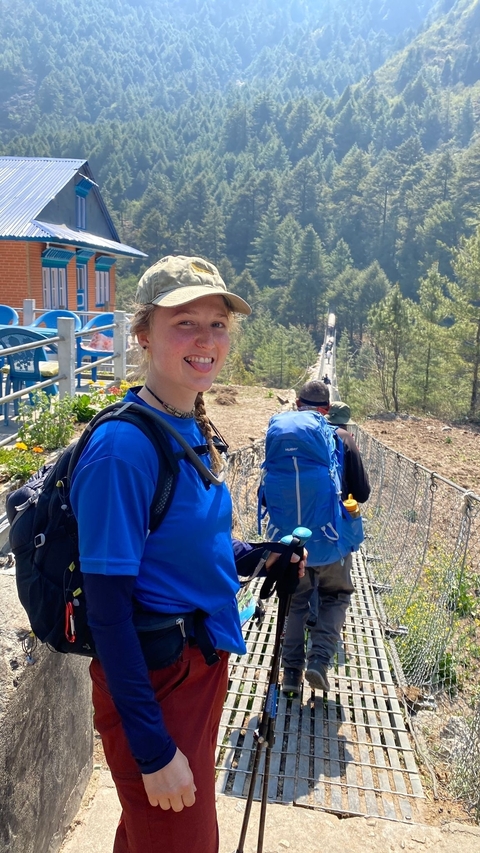 Hiker posing on a bridge with mountains in the background.