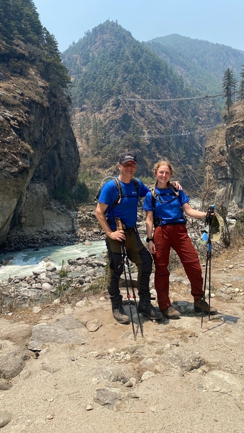 Two hikers posing with mountain rapids in the background.