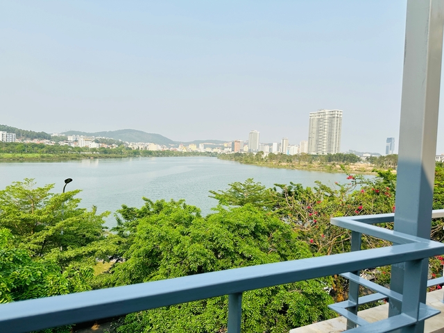       River view with trees and city buildings in the background.
  