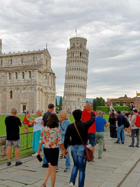 Crowd around the Leaning Tower of Pisa on a sunny day.