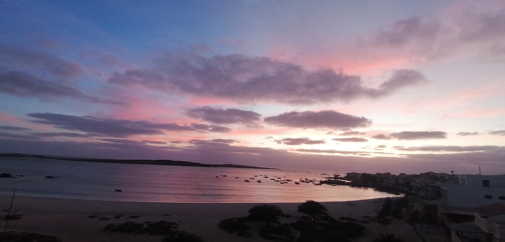 Dusk at a beach with a colorful sky and moored boats.