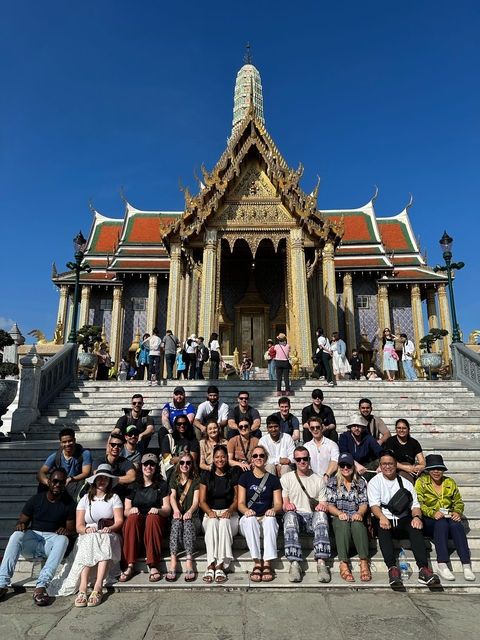 Group of people posing on steps in front of an ornate temple.
