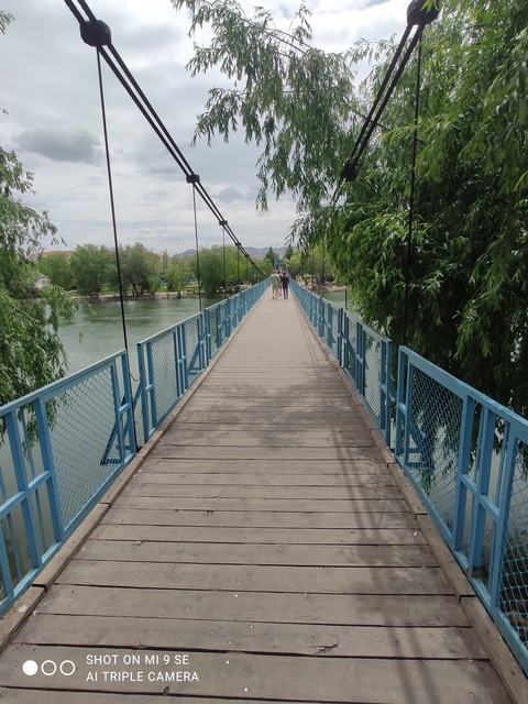       Long bridge over a river with people walking.
  