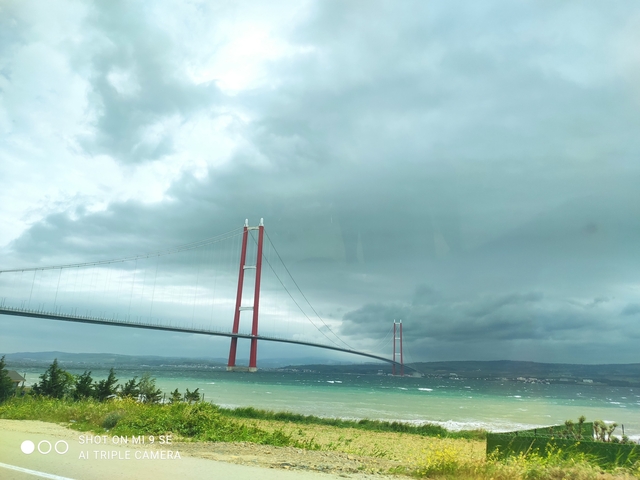       Suspension bridge over a choppy sea under a cloudy sky.
  