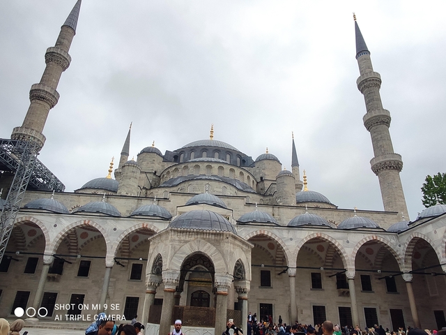       An iconic mosque with multiple domes and minarets against a cloudy sky.
  