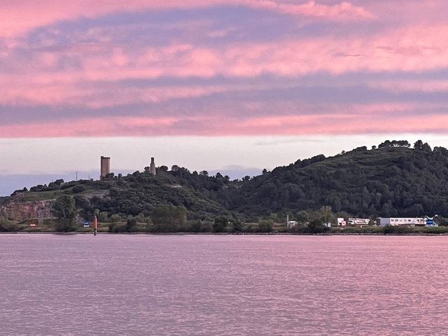       Sunset view of hills with ruins against a pink sky.
  