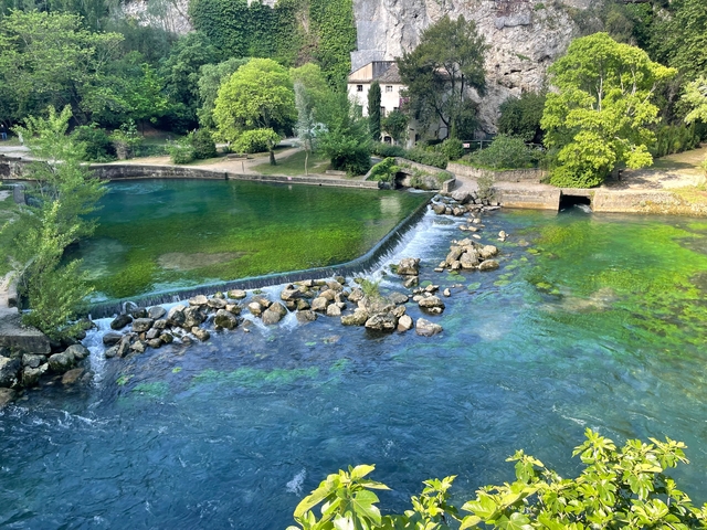       A picturesque river scene with a small waterfall and greenery.
  