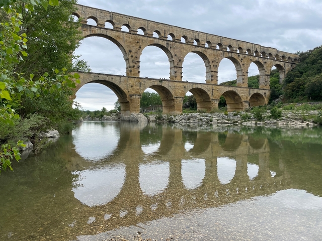       The Pont du Gard bridge spanning a clear river.
  