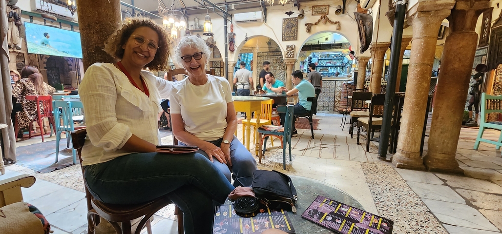 Two women sitting in a decorative interior cafe.