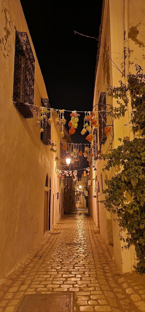 Street lit at night with colorful decorations.