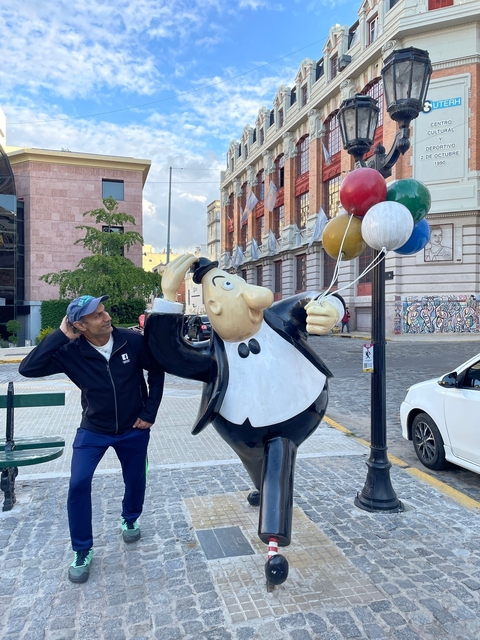 Man posing with a cartoon statue holding balloons