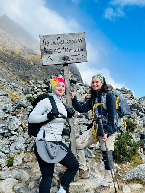 Two hikers smiling next to a directional sign.