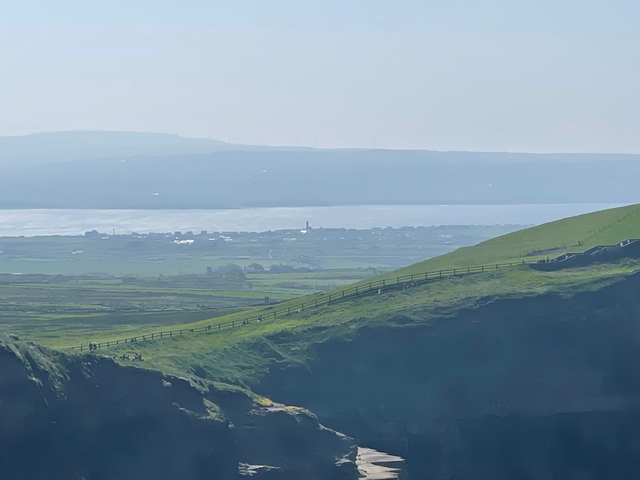 Scenic coastal view with distant town and sea.