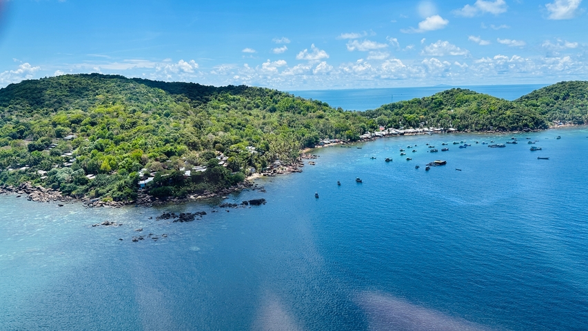       Lush green island surrounded by blue ocean waters.
  