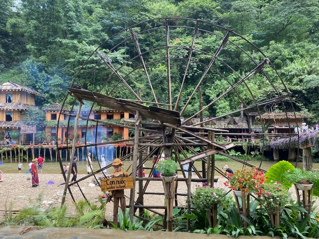       Local attraction with a wooden water wheel and people.
  