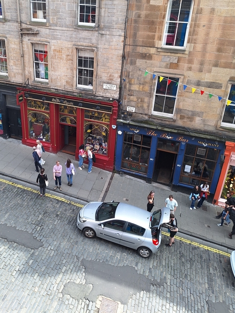 Street view with colorful shopfronts and people walking.