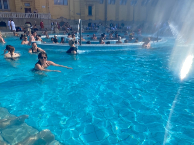 People swimming in a pool with fountains.