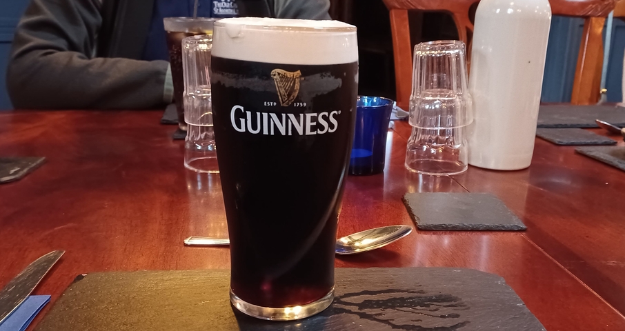 A pint of Guinness on a wooden table in a pub setting.