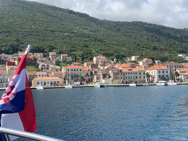 Scenic coastal town view from the water with boats and hills.