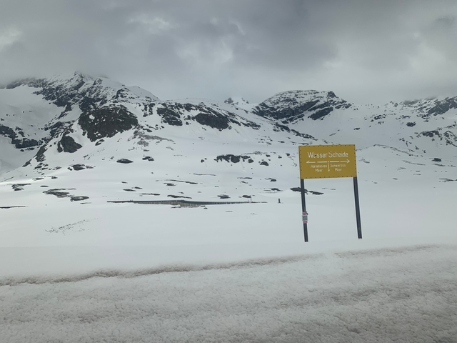 Snowy mountain landscape with a sign and snow-covered terrain.