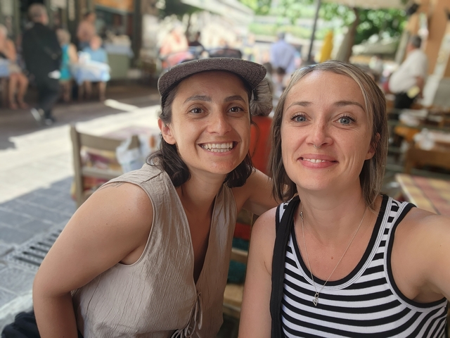 Two women smiling at an outdoor café.