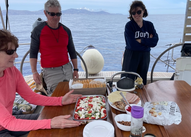      People enjoying a meal on a sailing yacht.
  