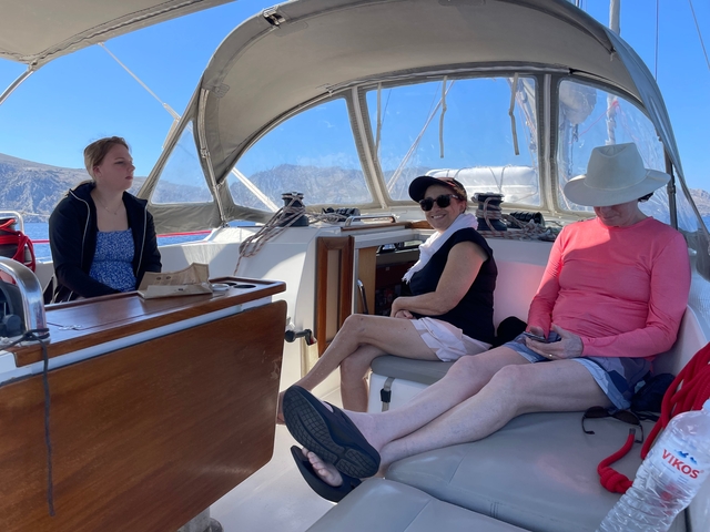       People relaxing in the cockpit of a sailing yacht.
  