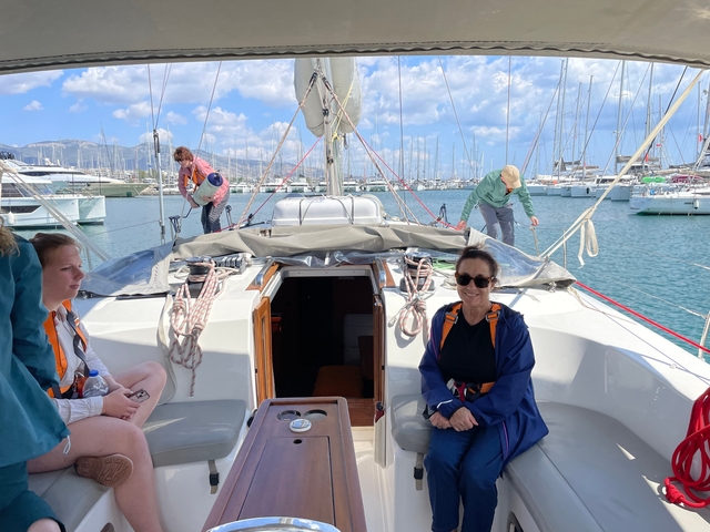       People on a yacht at a marina preparing to set sail.
  