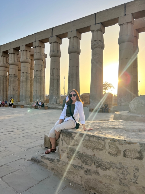 A person sitting among ancient columns at sunset.