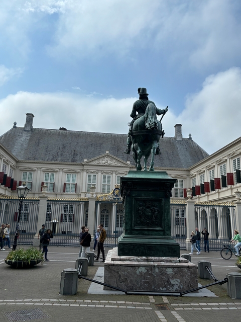       Statue of a horse and rider in front of a large building.
  