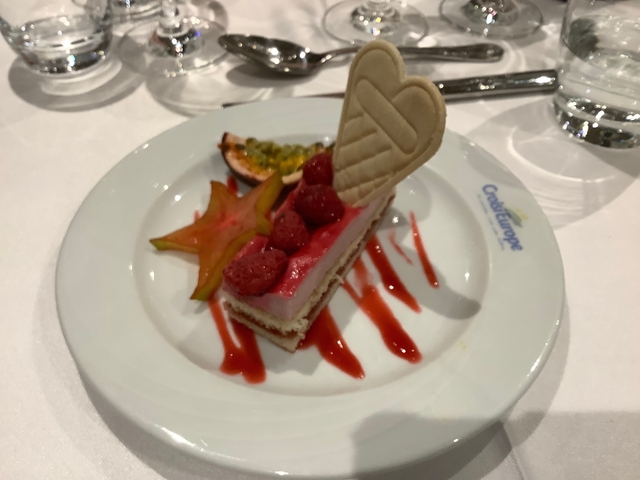 Dessert with raspberries, fruit slices, and wafer on a plate.
