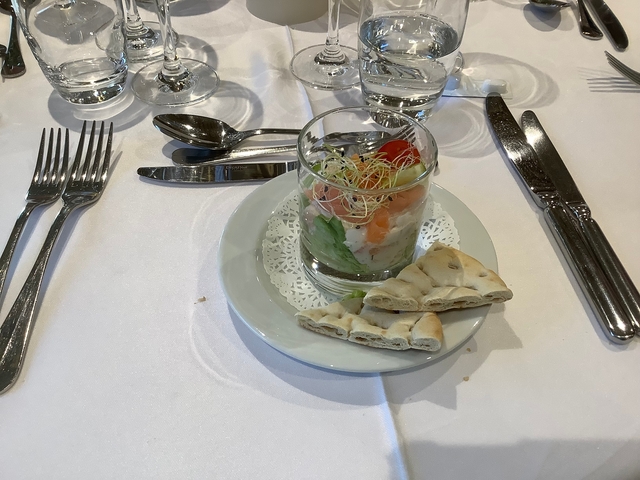 Appetizer in a glass with bread and garnish on a plate.