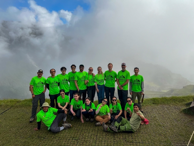 Group wearing matching green shirts posing with misty mountain view.