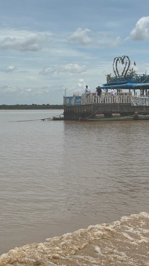 A calm river with a dock and boat in Cambodia.