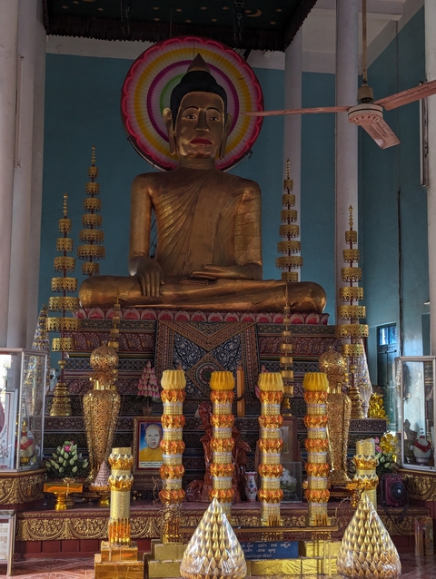 Golden statue of a seated Buddha with decorative items.