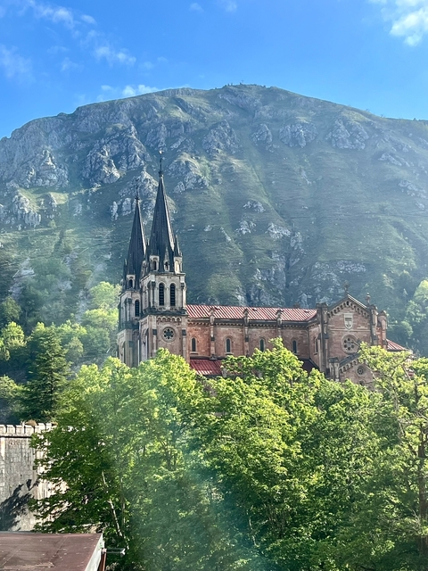       Large church with pointed towers set against a mountainous backdrop.
  
