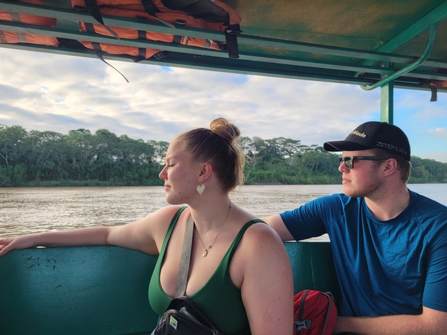       Two people on a boat enjoying a river view.
  