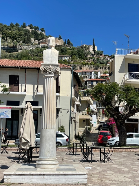      Column in front of buildings on a hill slope.
  