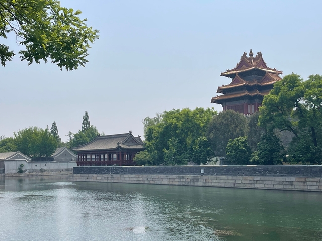       A traditional building near a canal surrounded by trees.
  