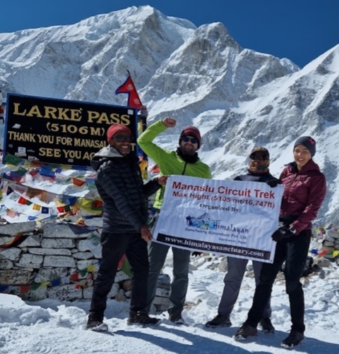       Four hikers posing with a sign at a high mountain pass
  