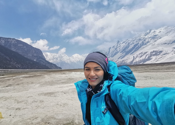       Selfie of a hiker with snowy mountain peaks in the background
  