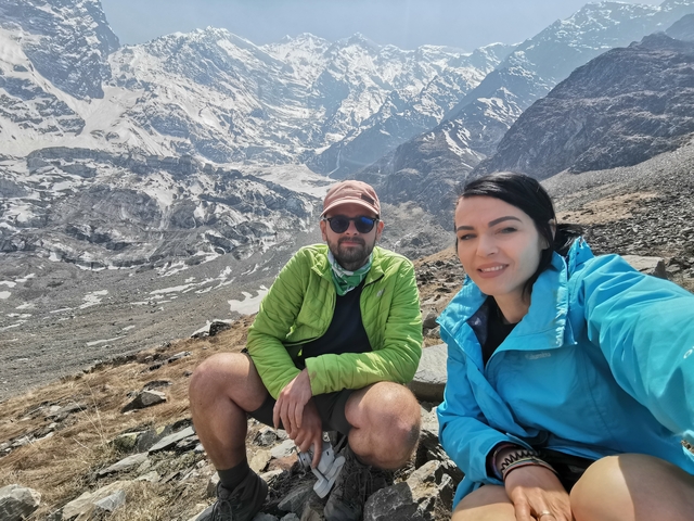       Two hikers sit on a rocky outcrop with a mountain view
  