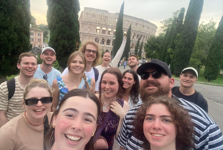 Group selfie with a famous ancient amphitheater in the background.