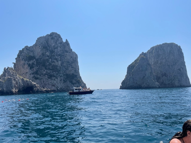 Boat sailing between two rock formations in clear blue water