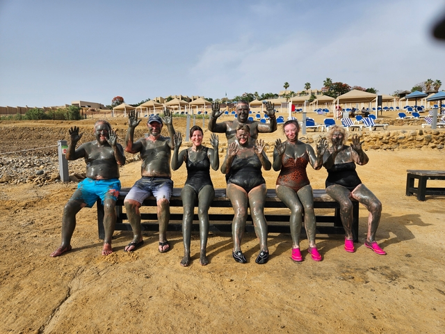 Group of people covered in mud by the Dead Sea.